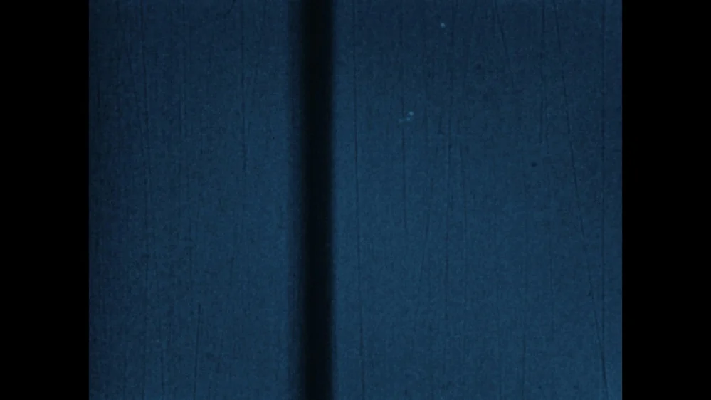 Quadro do filme de Tremonton: céu azul-acinzentado e granulado, com uma faixa escura vertical à esquerda e pequenos pontos claros quase imperceptíveis